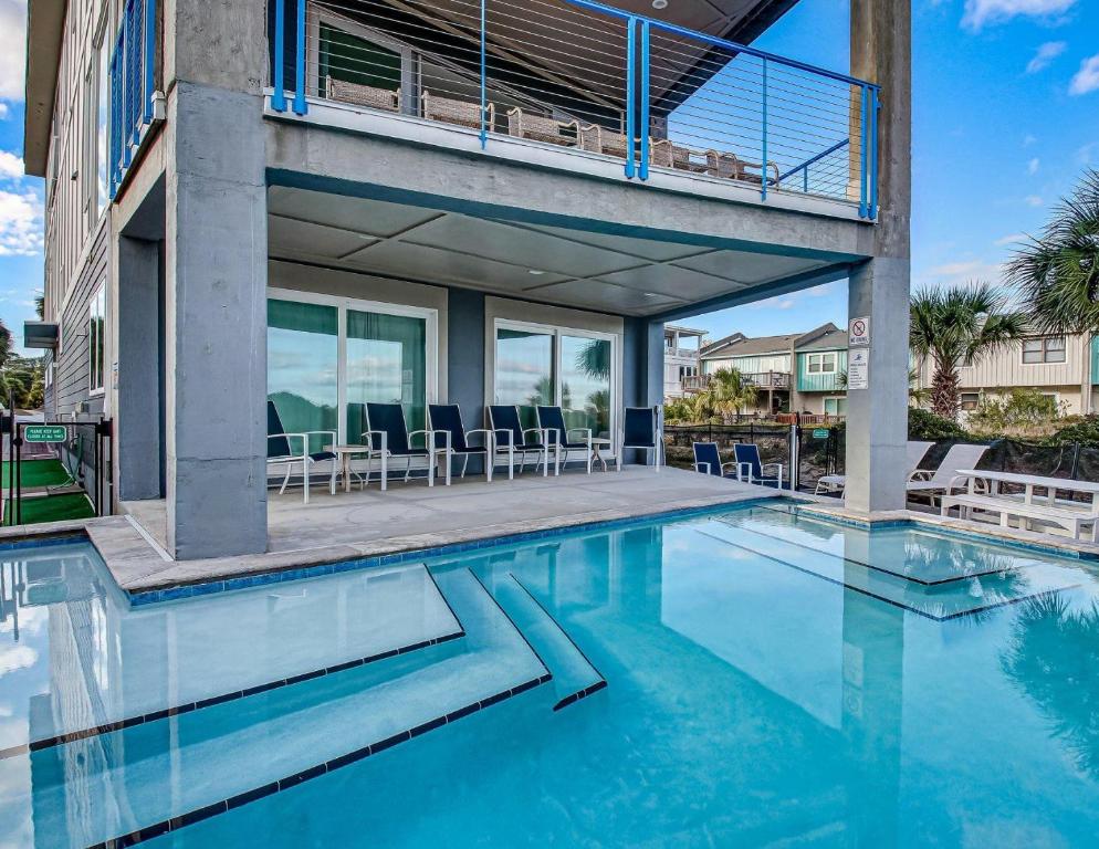 a house with a swimming pool with a balcony at Ocean View Modern in Tybee Island