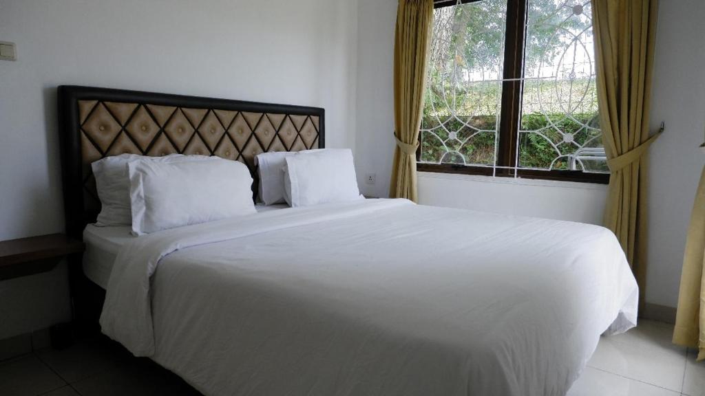 a white bed in a bedroom with a window at Villa Dalia Puncak Nc3-31 in Cikundul