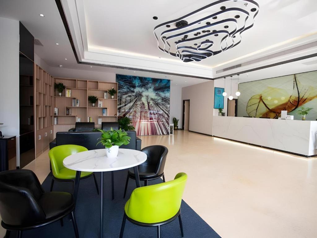 a dining room with a table and green chairs at GreenTree Inn Tangshan Nanhu International Exhibition Center in Tangshan