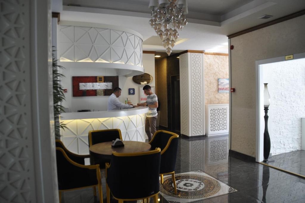 a dining room with a table and two people in the kitchen at Grand Sera Hotel in Ankara