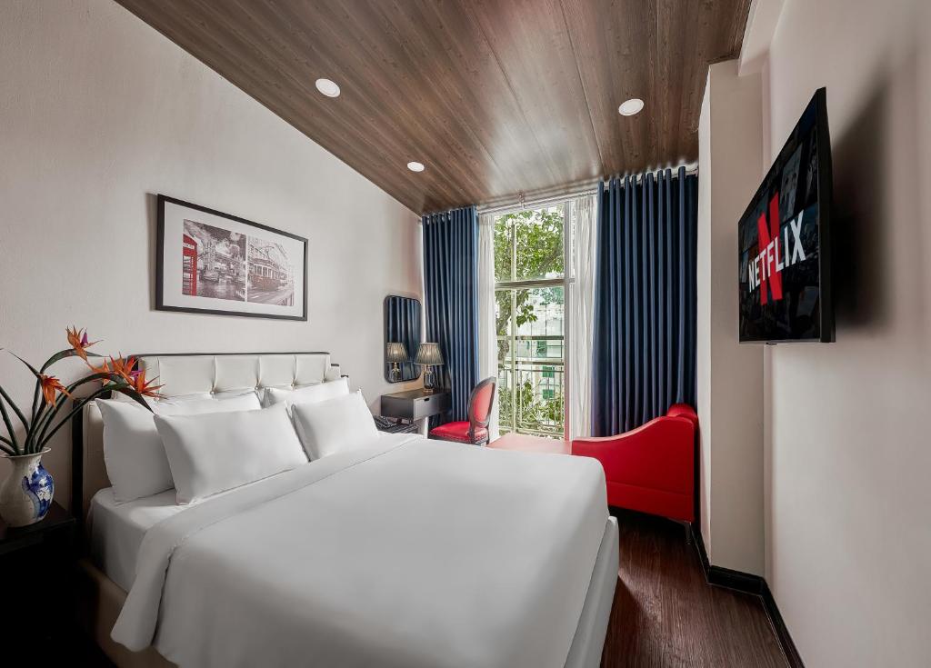a bedroom with a large white bed and a red chair at The Passion Suites Hotel & Spa in Ho Chi Minh City