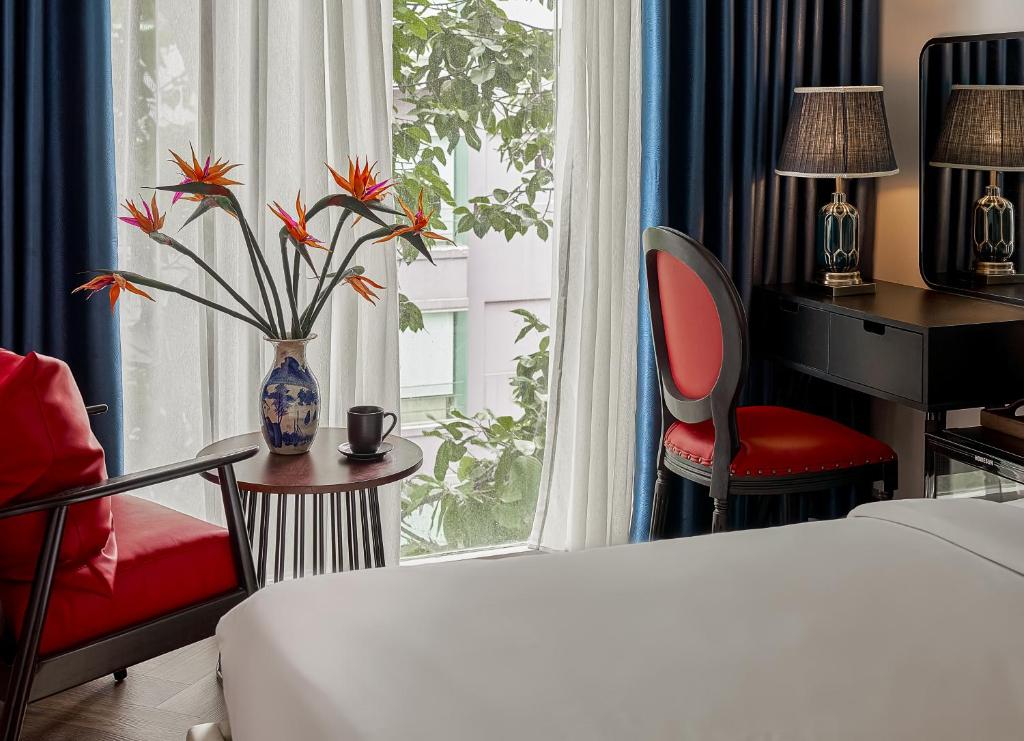 a hotel room with a bed and a desk and a window at The Passion Suites Hotel & Spa in Ho Chi Minh City
