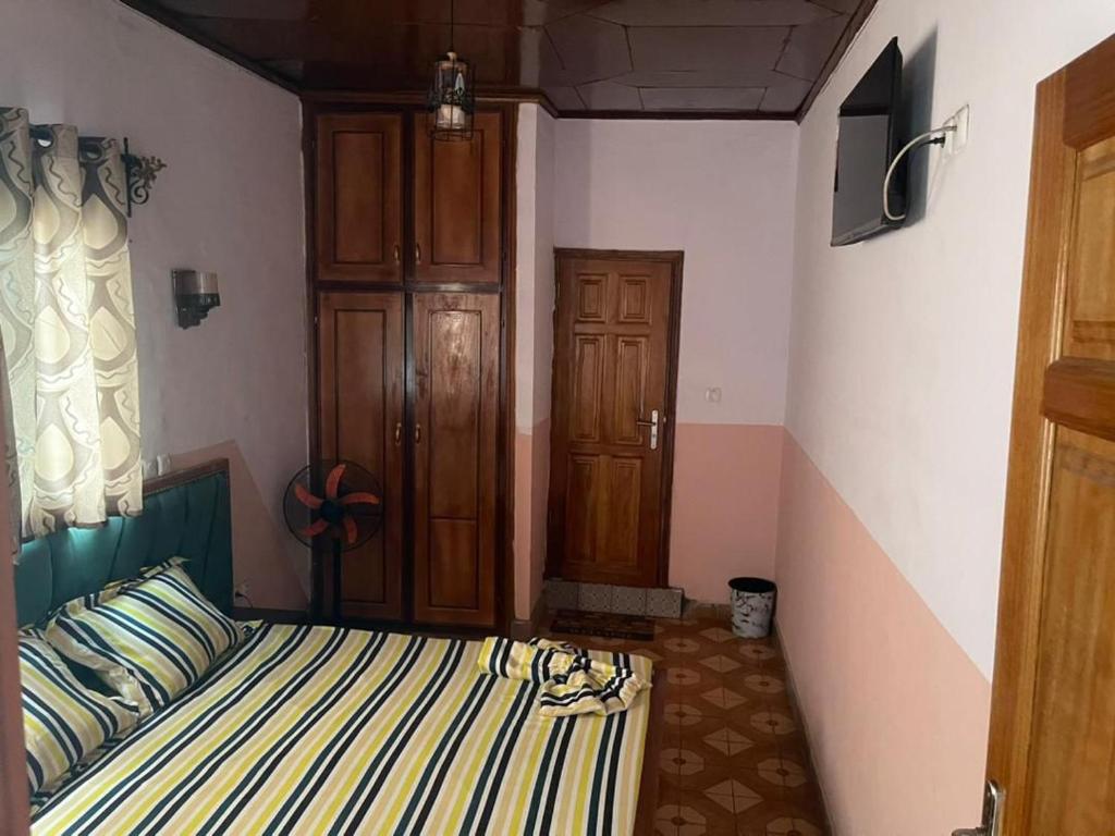 a bedroom with a bed with striped sheets and a window at Complexe la samaritaine 2 in Yaoundé