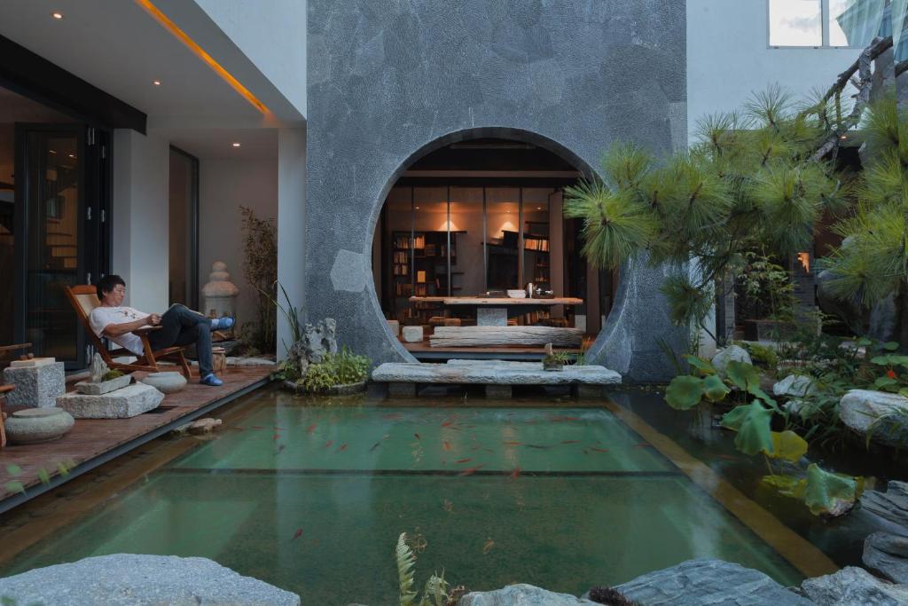 een man in een stoel naast een zwembad bij 大理古城归渊民宿 in Dali (oude stad)