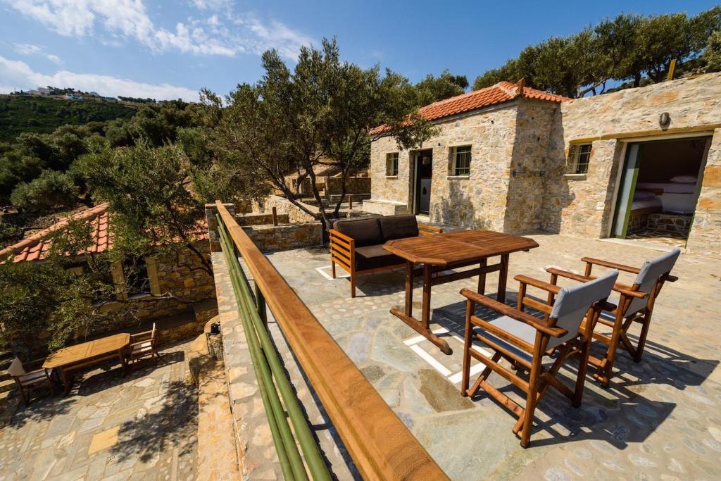 a patio with a wooden table and chairs on a building at Casa Milos Stone Chalets in Alonnisos