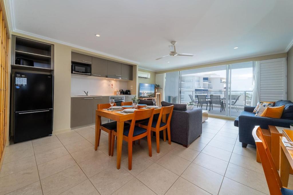 Luxury 2 Bedroom Apartment Beach Views Pool في Urangan: مطبخ وغرفة معيشة مع طاولة وأريكة