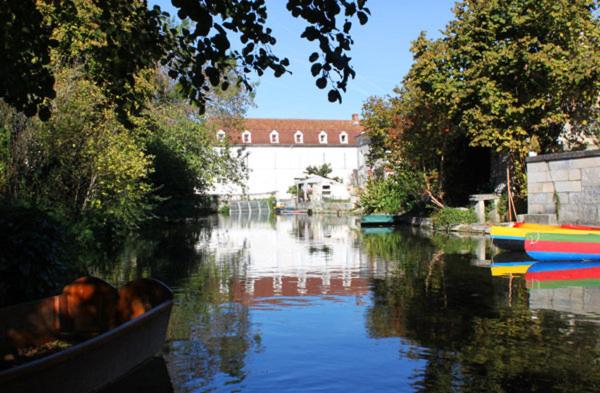 una barca su un fiume con un ponte sullo sfondo di Le Moulin de Bassac a Bassac