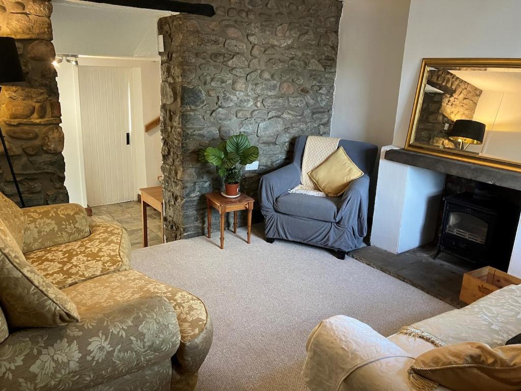a living room with a blue chair and a fireplace at Character Cottage in Usk in Usk