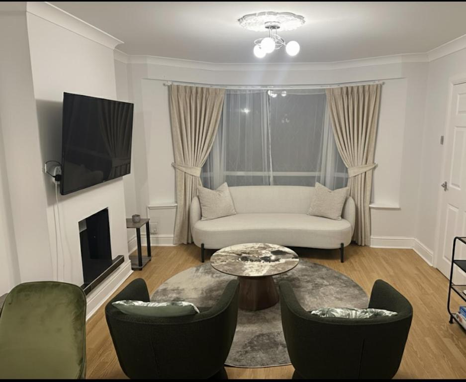 ボアハムウッドにあるCosy 4 bedroom in borehamwoodのソファとテーブルと椅子のあるリビングルーム