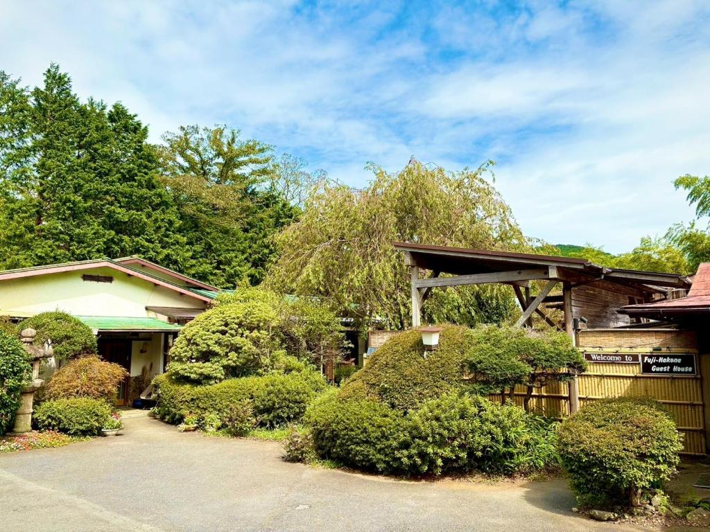 a house with a fence and some bushes at Fuji-Hakone Guest House in Hakone