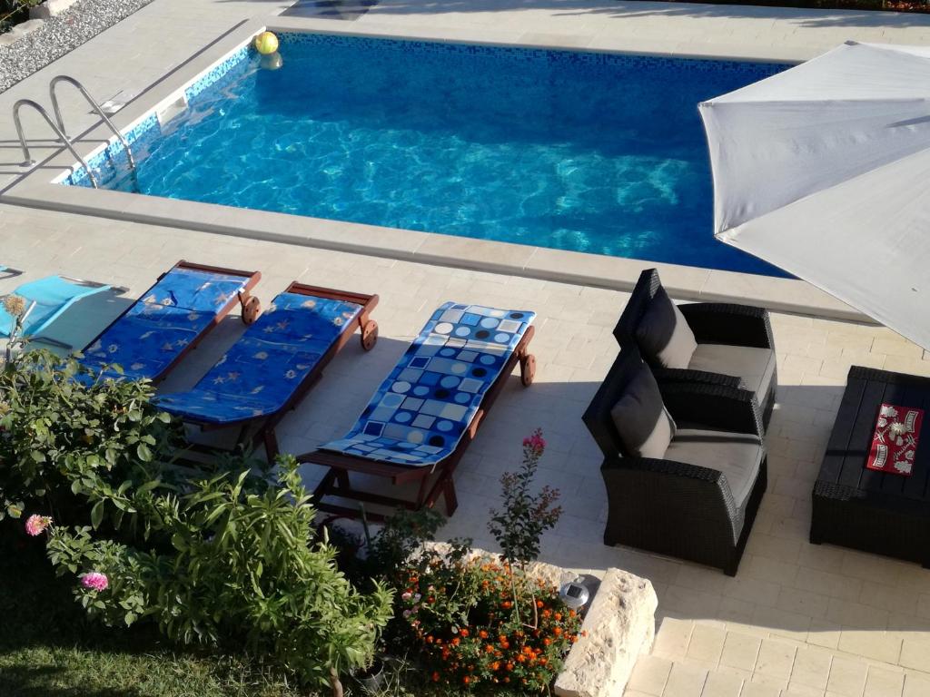 - une vue sur la piscine dotée de chaises longues et d'un parasol dans l'établissement Apartments Jankovic, à Vodice