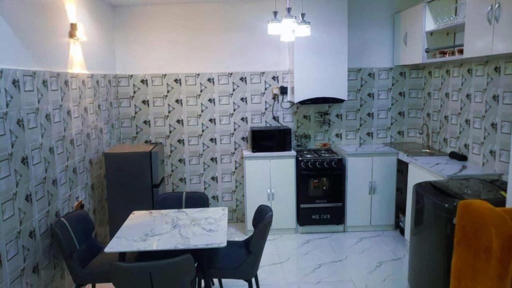 a kitchen with a table and chairs and a stove at Jade Luxe 2 Bedroom Apartment in Agbor