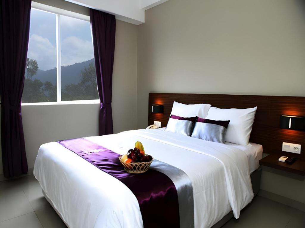 a bedroom with a bed with a bowl of fruit on it at Amantis Hotel in Demak