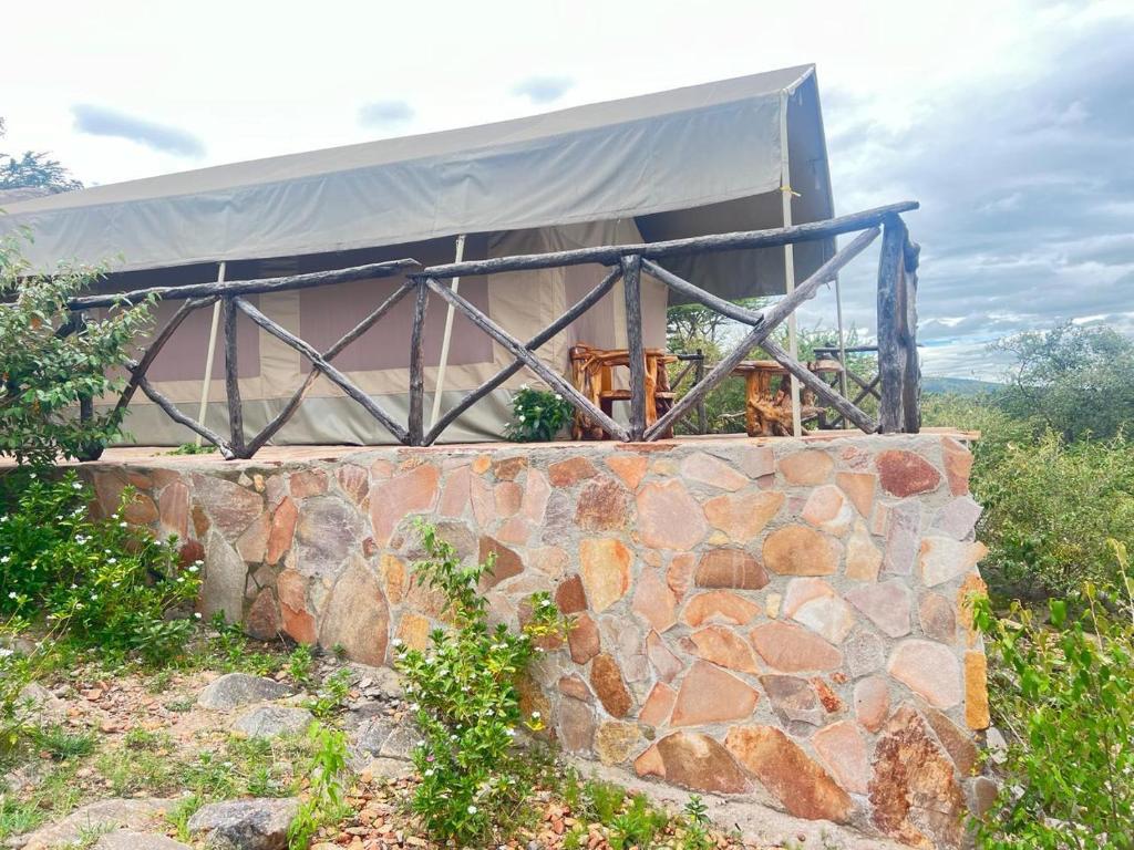 a building with a tent on top of a stone wall at Oloirien in Maasai Mara National Reserve