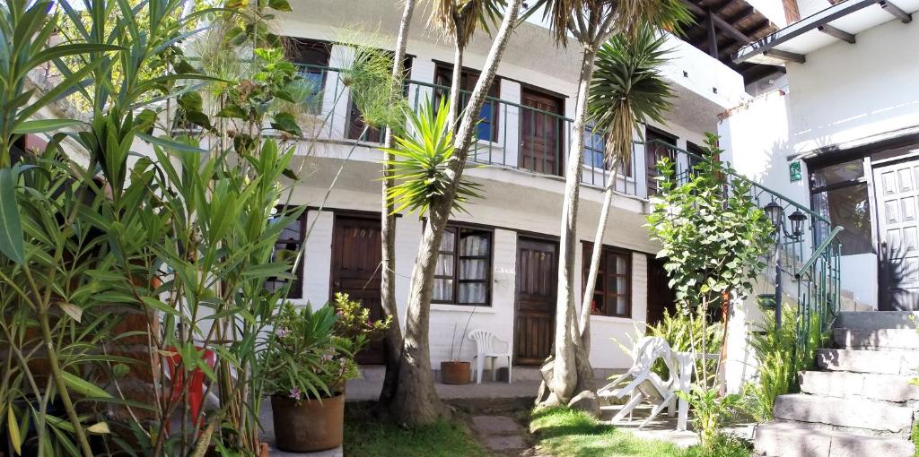 una casa blanca con palmeras delante en Hostal L'Auberge Inn en Quito