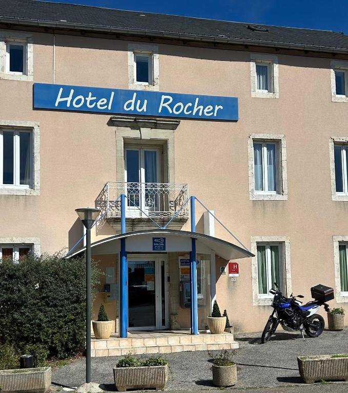 a hotel du rooster sign in front of a building at Hotel Du Rocher in Le Caylar