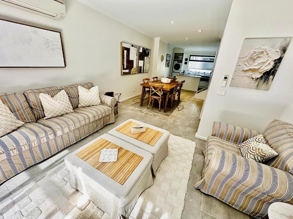 a living room with two couches and a table at Heart of Mornington in Mornington