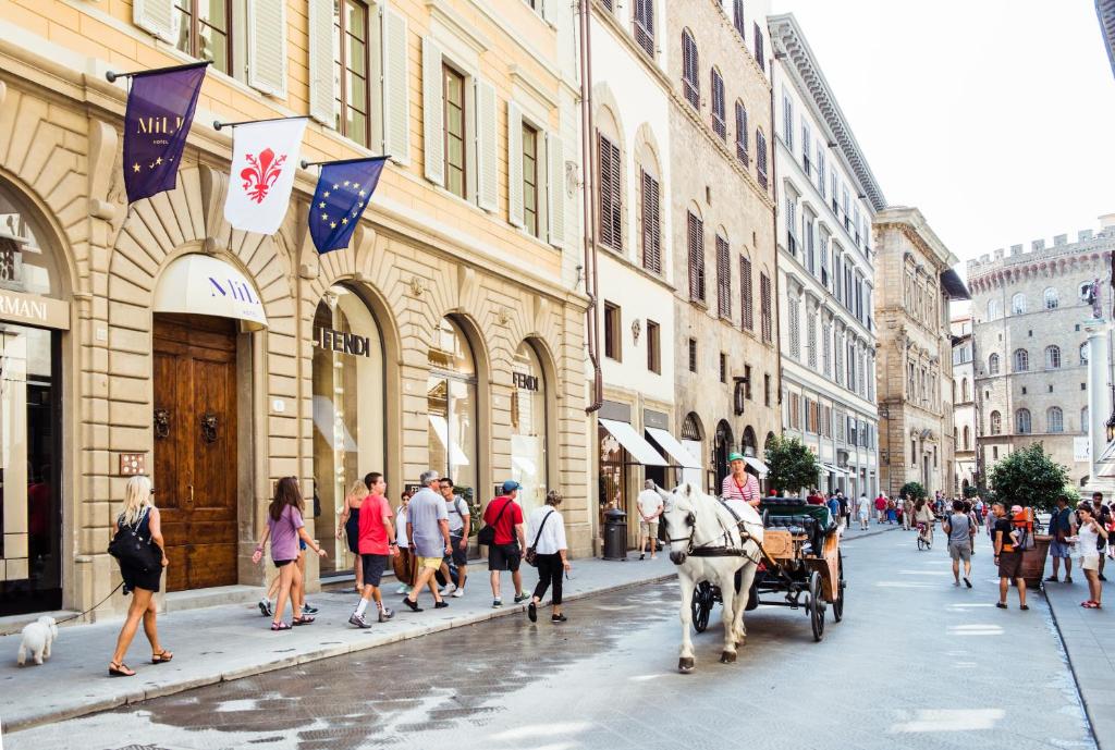 a horse drawn carriage on a city street with people at Hotel Milù in Florence