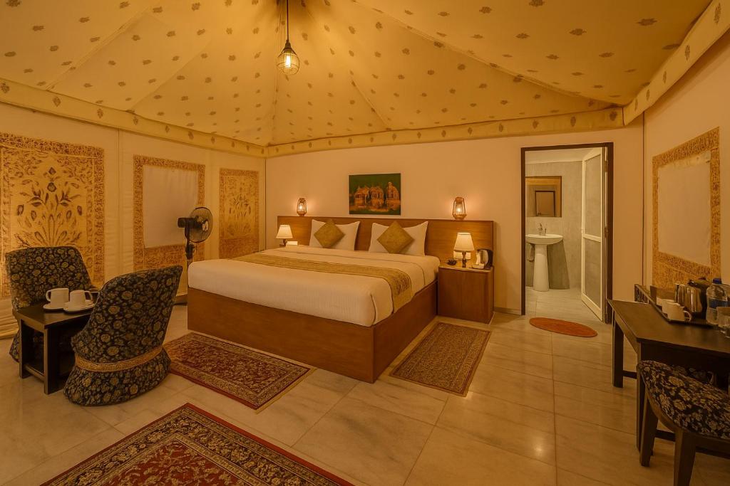 a bedroom with a bed and a desk and chairs at The Saffron Desert Camp, Jaisalmer in Jaisalmer