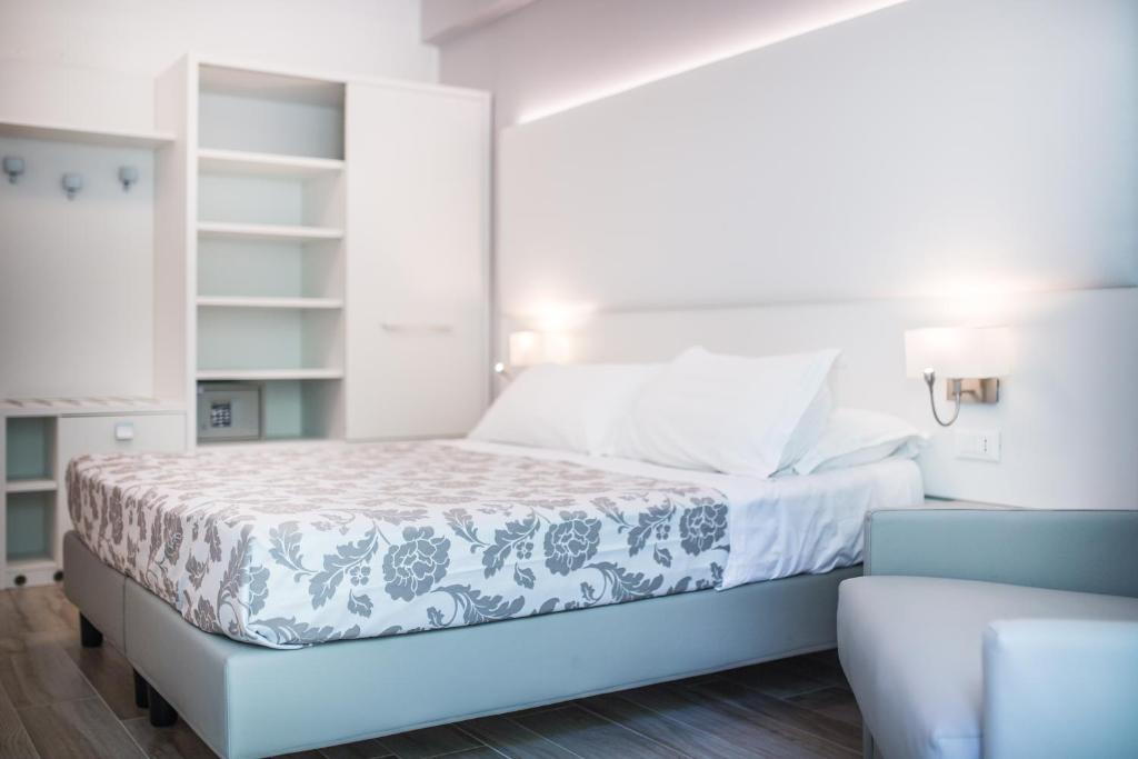 a white bedroom with a bed and a couch at Hotel Bologna in Lignano Sabbiadoro
