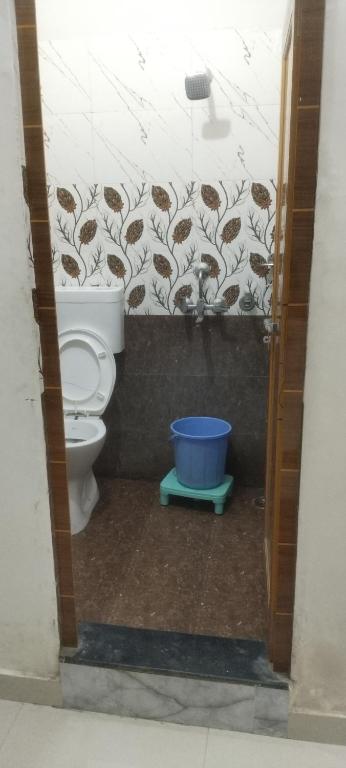 a bathroom with a toilet and a blue bucket at Kashi kedar paying guest house in Varanasi