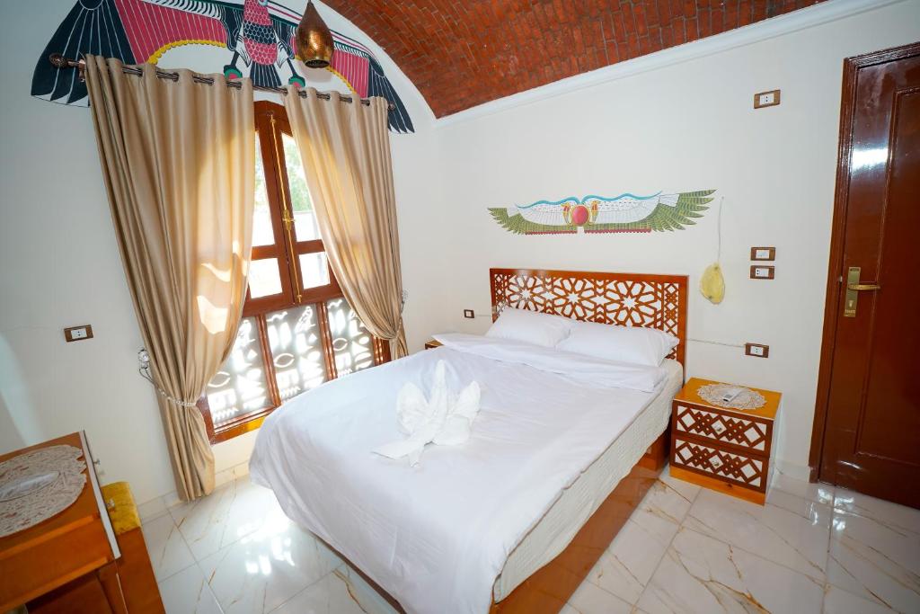 a bedroom with a bed with white sheets and a window at Osman Authentic Dome House Garden Retreat in Luxor