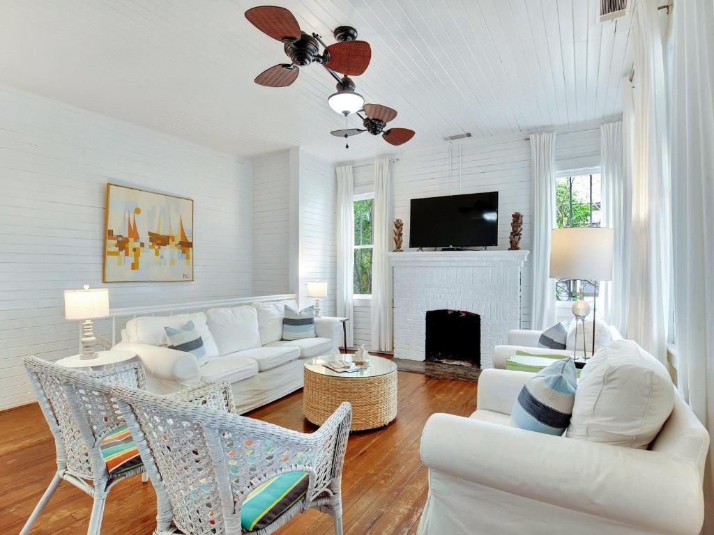 Una sala de estar con muebles blancos y chimenea. en Coast A While, en Tybee Island