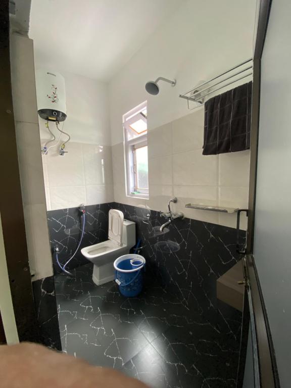 a bathroom with a toilet and a black tile floor at Norkyi Homestay in Tawang