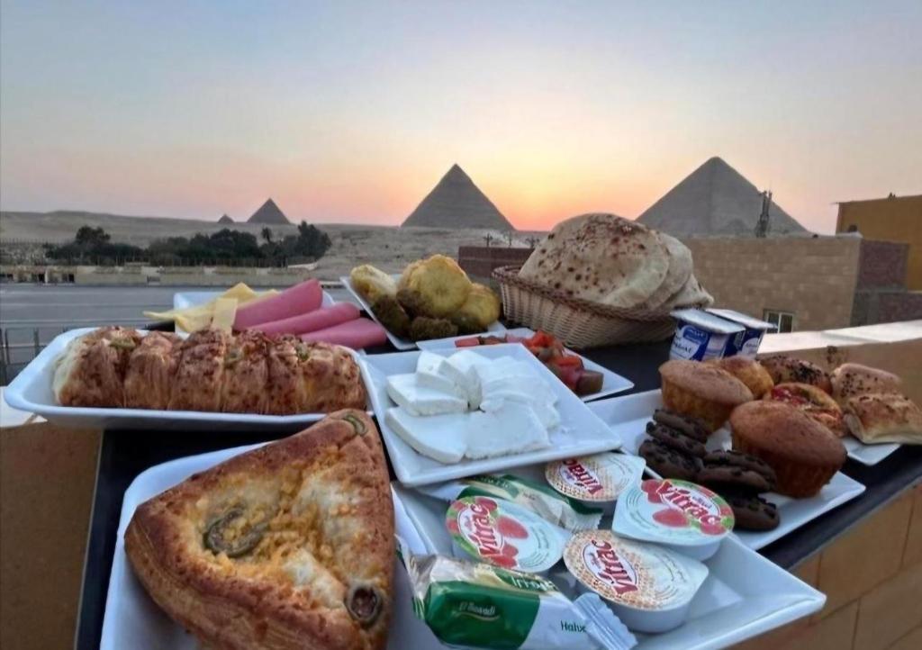 a table topped with plates of food with pyramids at Elgabry pyramids inn in Cairo