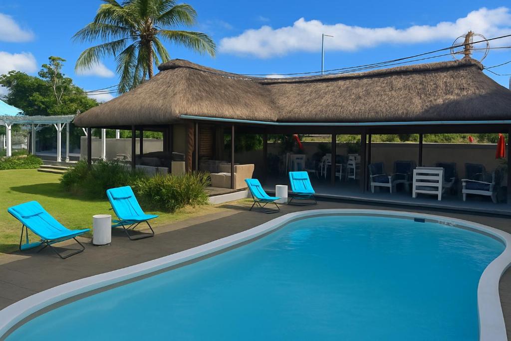 a swimming pool with blue chairs and a house at Stella Rina "Adults Only" in Grand-Baie