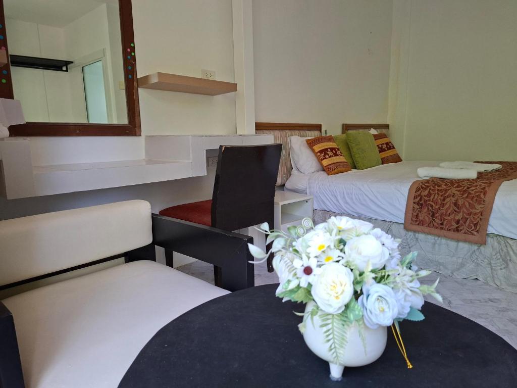 a room with two beds and a table with a vase of flowers at Suwita House in Nai Yang Beach