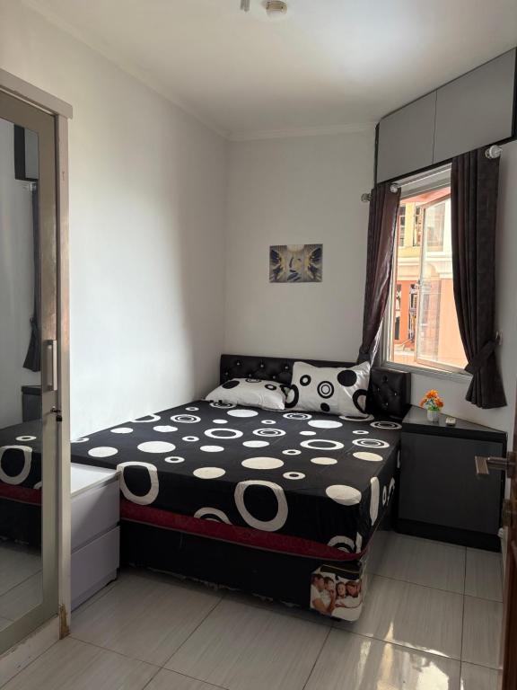 Un dormitorio con una cama con un edredón blanco y negro. en Cozy Room by StayIn Jakarta, en Yakarta