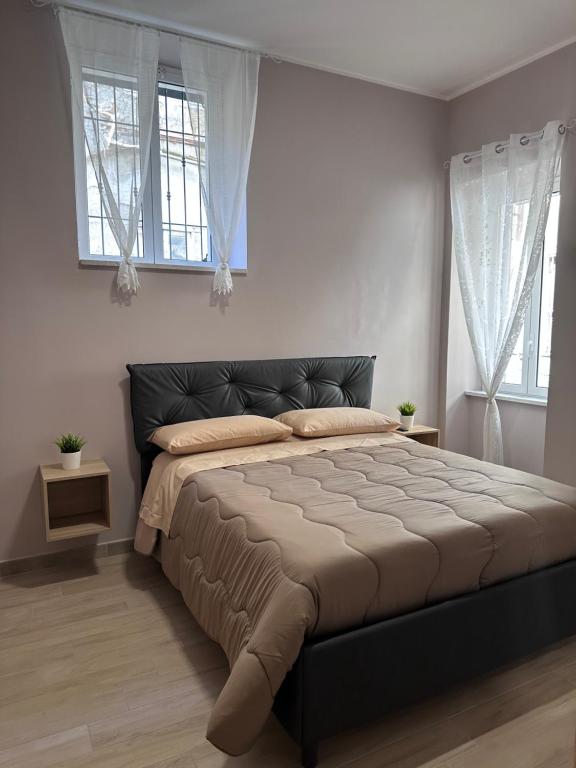 ein großes Bett in einem Schlafzimmer mit zwei Fenstern in der Unterkunft La Casetta di Nonno Cuono in Acerra