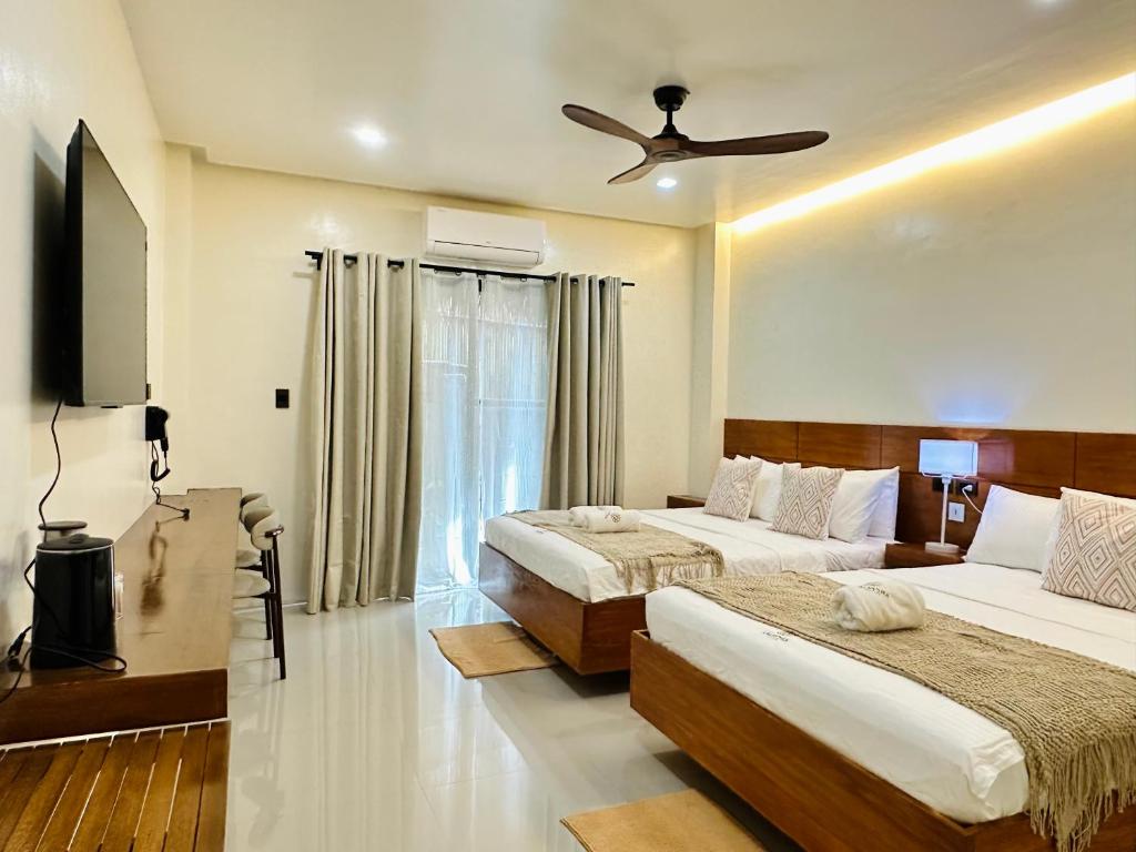 Un dormitorio con dos camas y un televisor de pantalla plana. en Calathea Suites El Nido, en El Nido