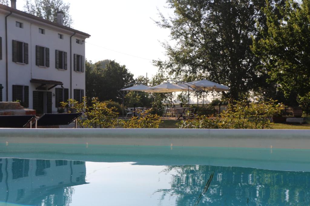 a pool of water with umbrellas and a building at Agriturismo Viridarium in Castellucchio