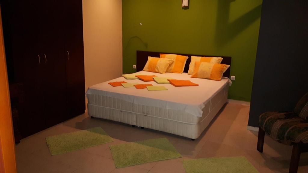 ソゾポルにあるGuest House Dimaの緑の壁のベッド1台、オレンジの枕が備わるベッドルーム1室が備わります。