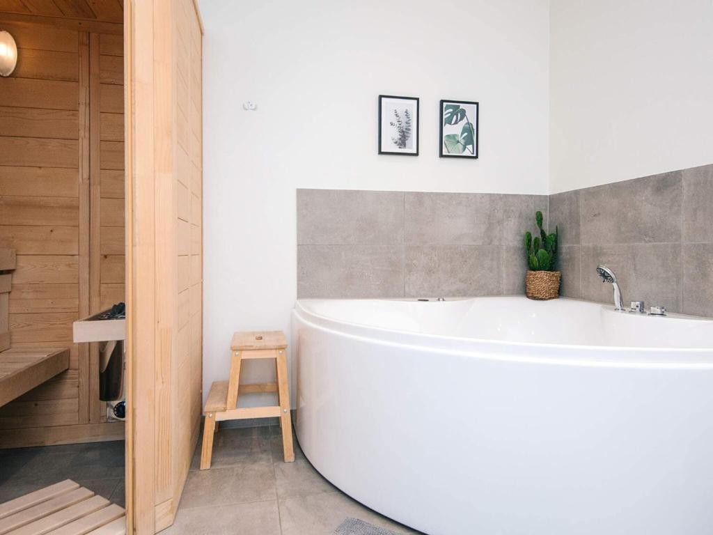a white bath tub in a bathroom with a stool at 8 person holiday home in Ringkøbing in Ringkøbing