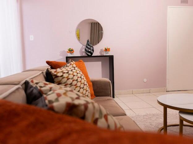 een woonkamer met een bank en een spiegel bij Bright and airy Harare CBD flat in Harare