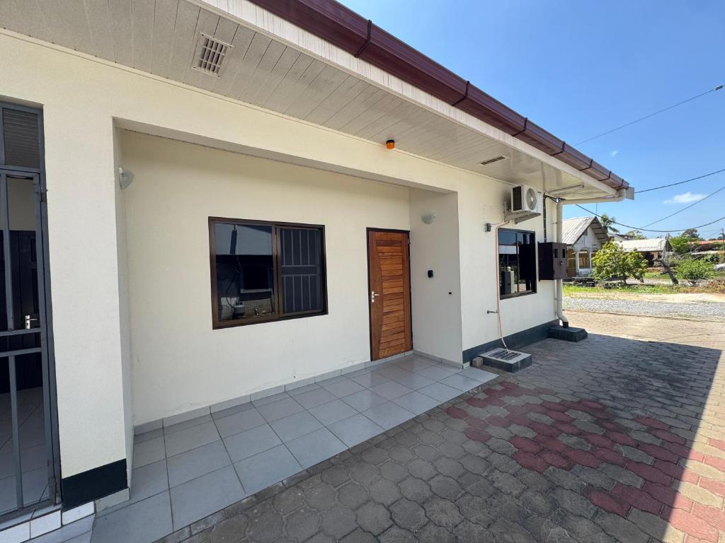 a white house with a door and a patio at Solace Sranan, Modern 2Bedroom Apartment with Garden View near Paramaribo in Wanica