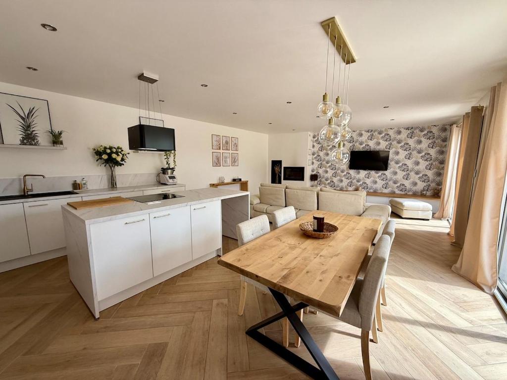 a kitchen and living room with a wooden table and a dining room at Maison Familiale plain pied à 2km de la mer in Trignac