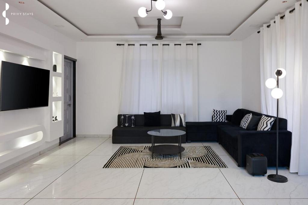 een woonkamer met een zwarte bank en een tafel bij Privy Stays- Cavo Villa, Alibag in Mān