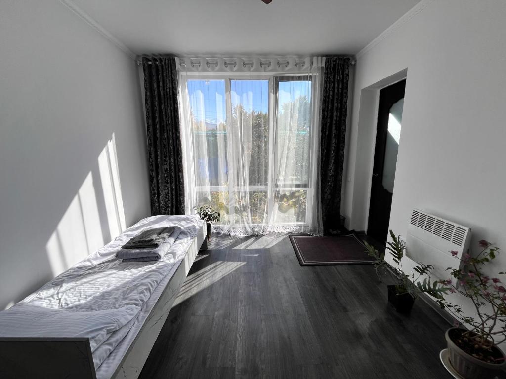 une chambre avec un lit et une grande fenêtre dans l'établissement Tiny Stay, à Karakol