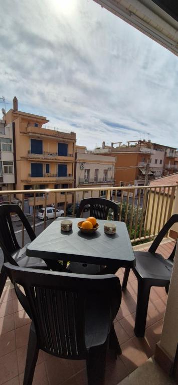Una mesa con un bol de fruta en un balcón. en Casa Travaglianti - Letojanni Taormina, en Letojanni