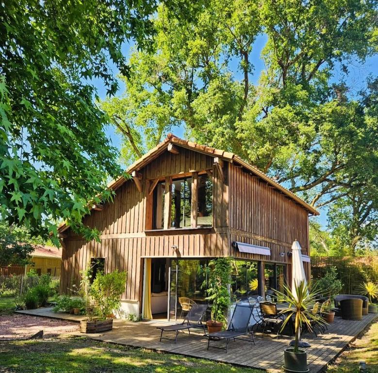 a large wooden house with a patio in front of it at Villa Rustique Le Carriou in Léon