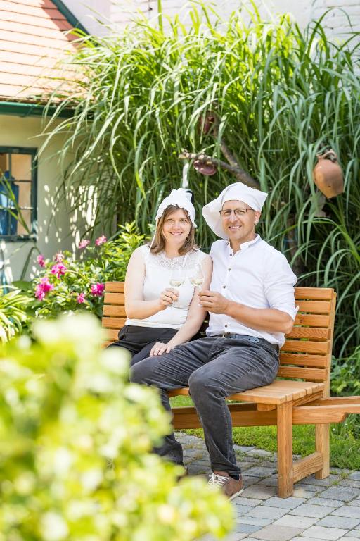 a man and a woman sitting on a bench at Weingut zur Schlafmütze in Herrnbaumgarten