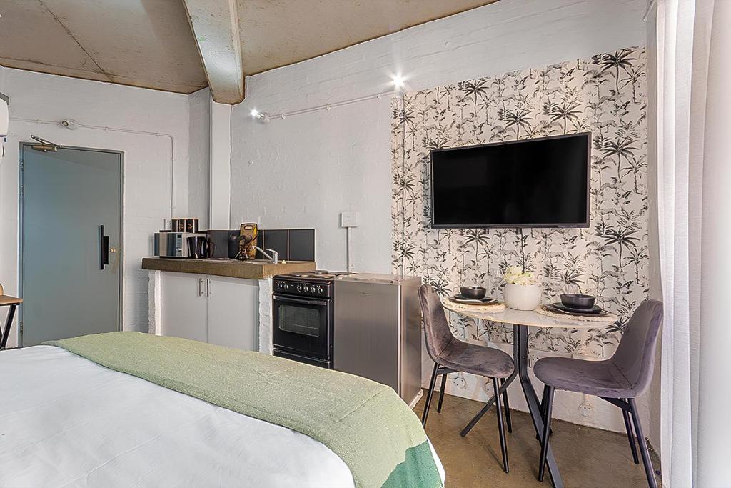 a bedroom with a bed and a table and a tv on a wall at Views From The 214 in Johannesburg