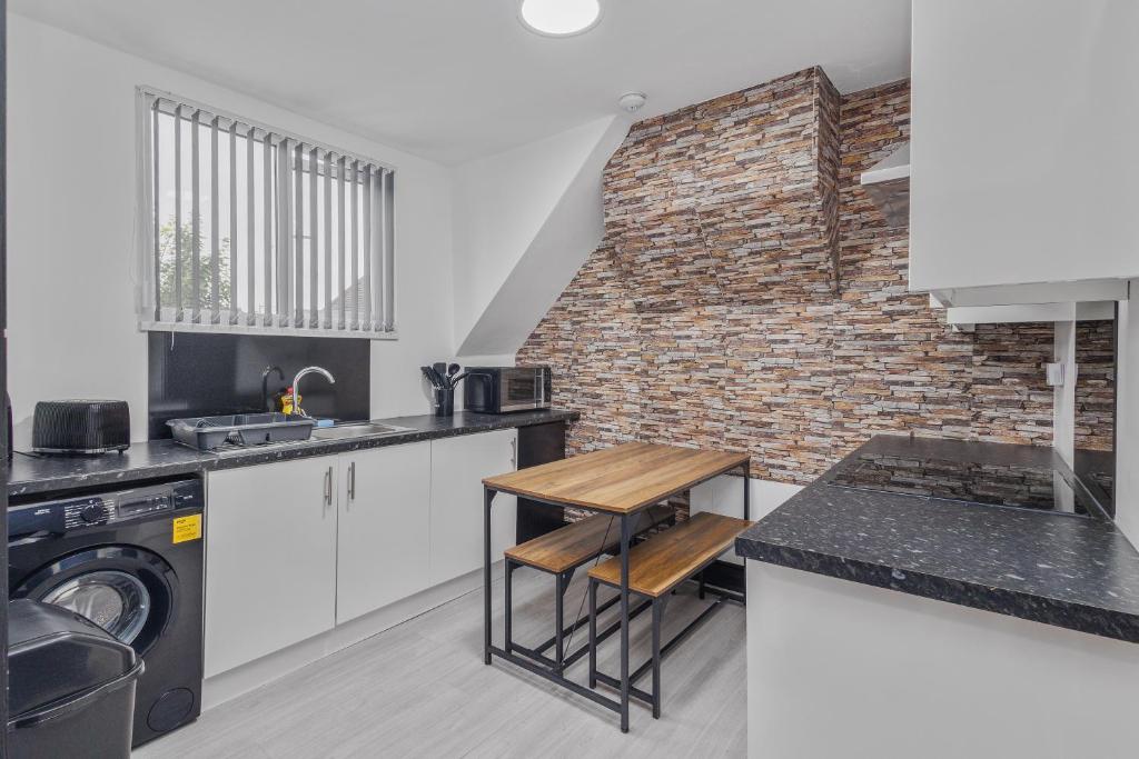 a kitchen with white cabinets and a brick wall at Luxury 2BR Retreat Sheldon in Sheldon