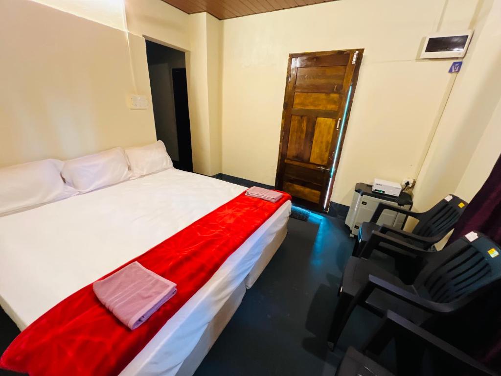 a bedroom with a bed and two black chairs at Siilver Sands Hutt Homestay - Malpe Beach in Malpe
