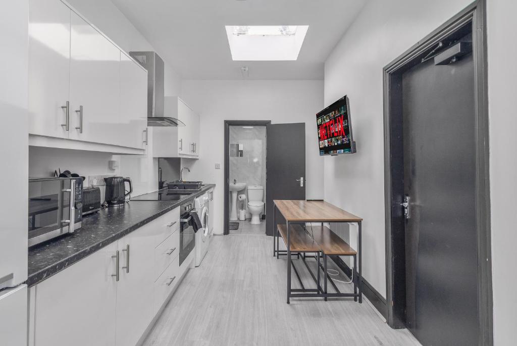 SheldonにあるStylish 2BR Apartment in Sheldonの白いキャビネットとテーブル付きのキッチンが備わります。