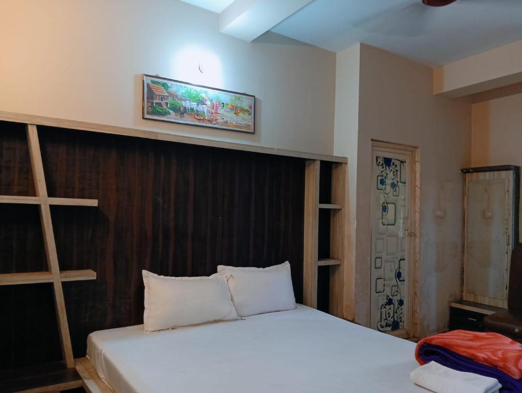 a bedroom with a white bed with a wooden headboard at Hotel Raj 